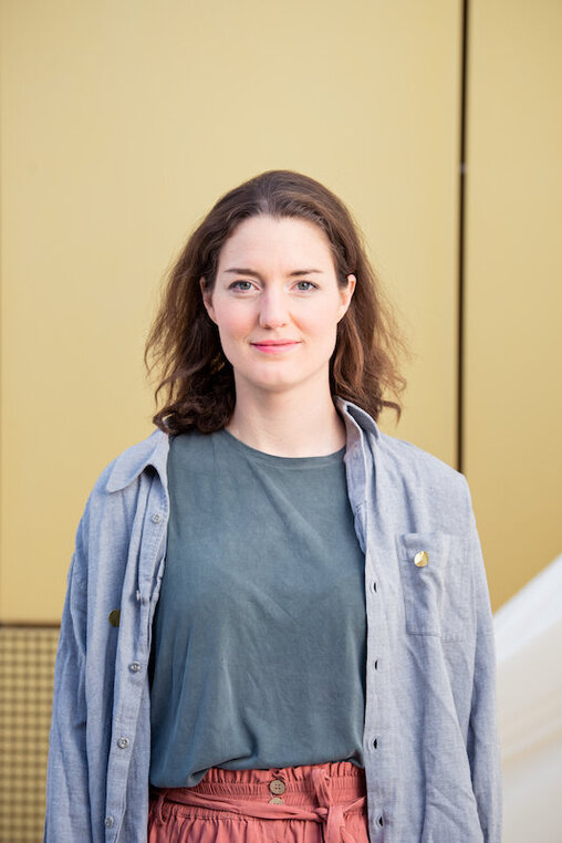 Elisa Merkens, künstlerische Leiterin des Theater Pfütze vor der goldenen Hausfassade