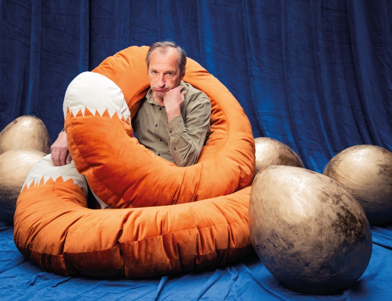 Der große böse Fuchs. Schauspieler Jürgen Decke sitzt als Fuchs verkleidet mit einem riesigen Fuchsschwanz zwischen goldenen Eiern und guckt gelangweilt bis frustriert